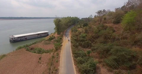Pullback shot over motorbikes riding on a small road along the riverbank Stock Footage