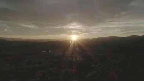 Pullback shot of a sunset over a small industrial town, creates lens flare, 4K Stock Footage 73699447
