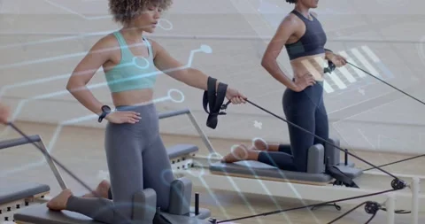 Pullback showing two women kneeling on pilates reformers pulling straps for core Video stock 333904714