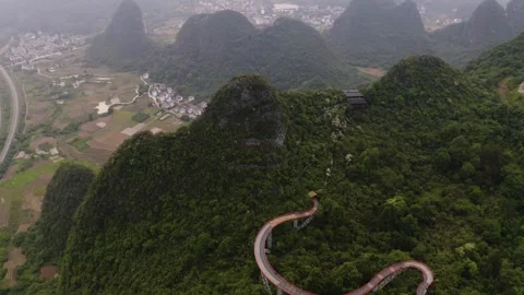 Pullback Tilt Down Over Curving Skybridge in Yangshuo Misty Valleys Stock-Footage 329031114