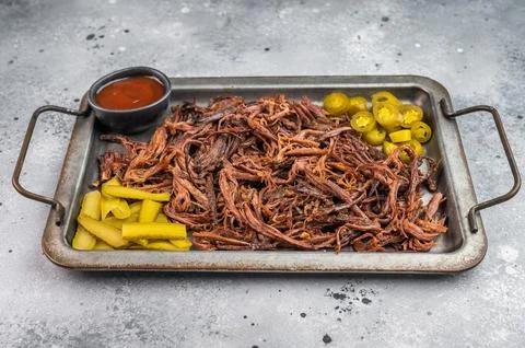 Pulled beef brisket with barbecue sauce, jalapeno and pickles on metal tray.. Stock Photos