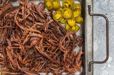 Pulled beef brisket with barbecue sauce, jalapeno and pickles on metal tray.. Stock Photos