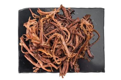 Pulled beef brisket jerky on black serving plate, dried meat snack close up.. Stock Photos