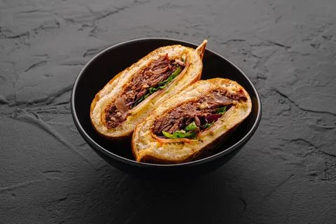 Pulled beef sandwich in black ceramic bowl with fresh ingredients and flavors Stock Photos