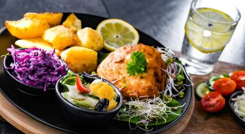 Pulled chicken cutlet coated with breadcrumbs with potatoes and vegetable sal Stock Photos