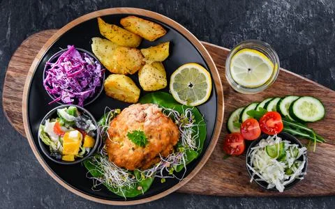 Pulled chicken cutlet coated with breadcrumbs with potatoes and vegetable sal Stock Photos