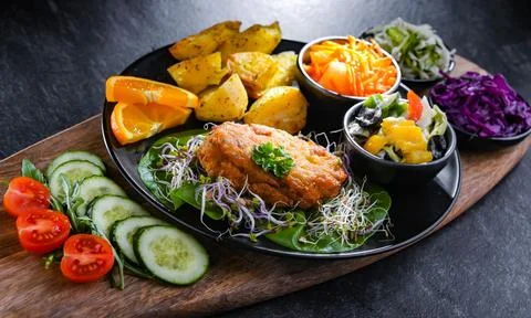 Pulled chicken cutlet coated with breadcrumbs with potatoes and vegetable sal 写真素材