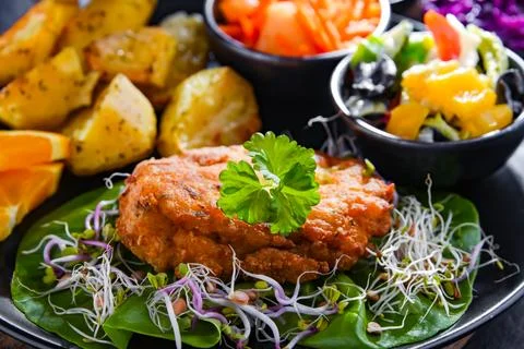 Pulled chicken cutlet coated with breadcrumbs with potatoes and vegetable sal 写真素材