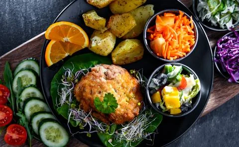 Pulled chicken cutlet coated with breadcrumbs with potatoes and vegetable sal 写真素材