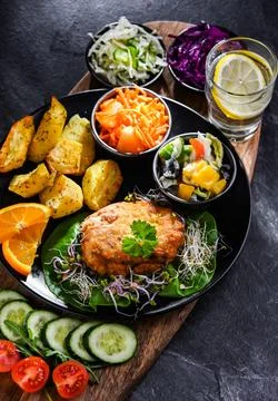 Pulled chicken cutlet coated with breadcrumbs with potatoes and vegetable salads 写真素材
