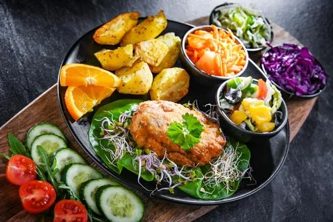 Pulled chicken cutlet coated with breadcrumbs with potatoes and vegetable salads 写真素材