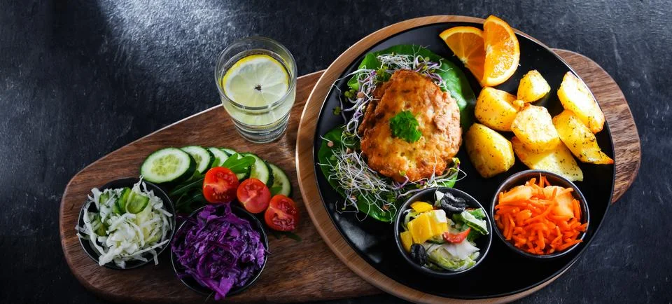 Pulled chicken cutlet coated with breadcrumbs with potatoes and vegetable sal 写真素材