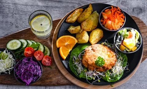 Pulled chicken cutlet coated with breadcrumbs with potatoes and vegetable sal 写真素材