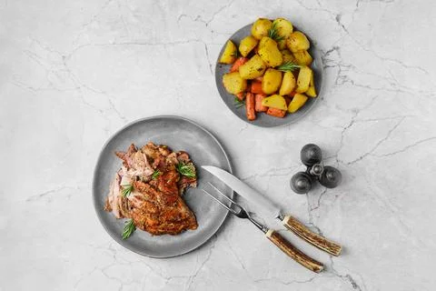 Pulled lamb meat baked in oven with potato and carrot on marble table Stock Photos