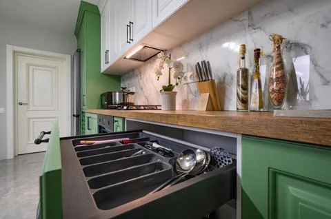 Pulled out drawer wih kitchen utensils at new green kitchen Stock Photos
