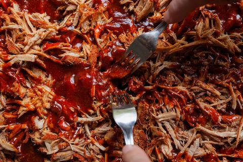 Pulled pork with barbecue sauce with being shredded with two forks Stock Photos