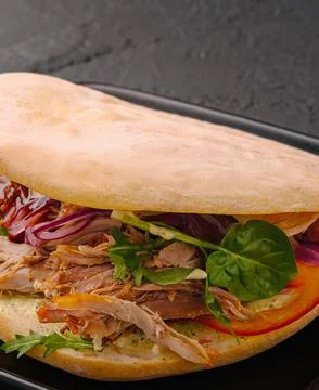 Pulled pork sandwich with fresh vegetables on dark background Stock Photos