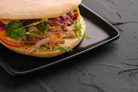 Pulled pork sandwich with fresh vegetables on dark background Stock Photos