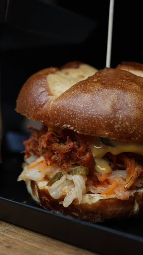 Pulled pork sandwich with tender shredded meat and melted cheese in a toasted bu Видео 346973756
