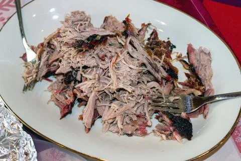 Pulled pork served on white plate with fork and crispy bark pieces Stock Photos