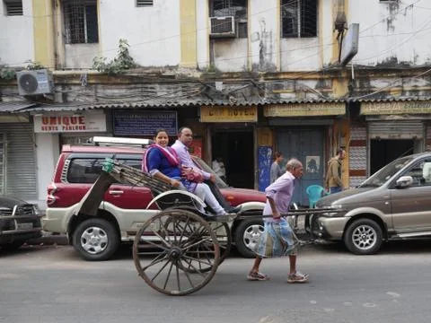A pulled rickshaw with two customers being pulled along the road. Foto stock