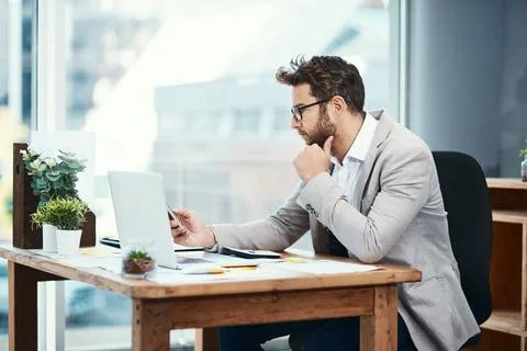 Pulling apart some thoughts and ideas. a young businessman working on a laptop Stock Photos