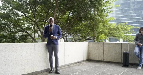 Pulling back African American man and man with suitcase calling on phones on Stock Footage 336173910