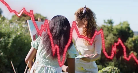Pulling back showing two women mixing paint, painting canvas for art while red Stock Footage 320126032