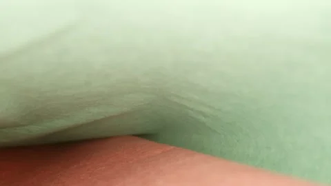 Pulling back from underneath a sheet of green tissue paper as it is folder Stock Footage 211264468