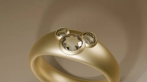 Pulling camera back revealing rotating gold ring with three bezel gems on beige Stock Footage 339194329