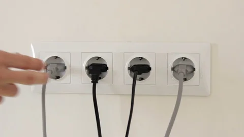 Pulling electric plugs out of the white wall socket Stock Footage 128229298