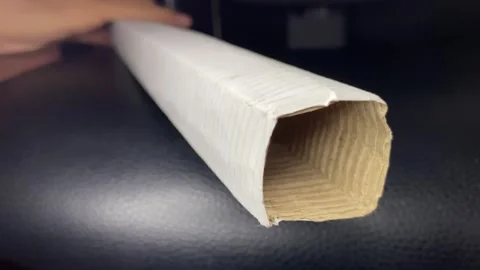 Pulling fluorescent tube light from paper package on black surface indoor. Stock Footage 251165997