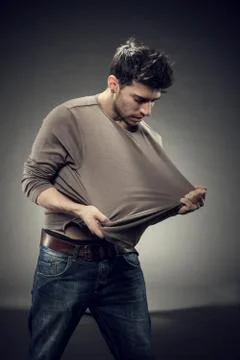 Pulling his tshirt for creating copy space Stock Photos