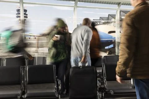 Pulling luggage, fast motion blur and hectic travelers in busy airport terminal Stock Photos