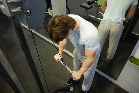 Pulling man cable machine exercise. Workout Routine With Personal Trainer Stock Photos