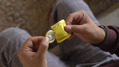 Pulling out a condom from the packet with fingers. Stock Footage 328213134