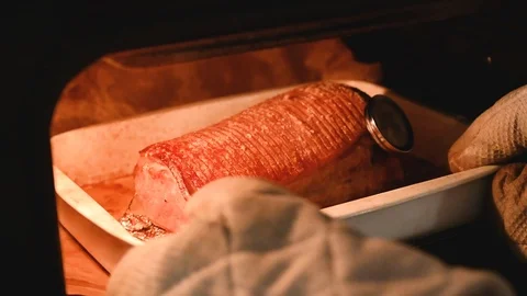 Pulling out roast pork from oven where it has been cooked Stock Footage 116228551