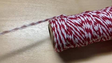 Pulling red and white twine thread close up shot on wooden table. Video stock 248205379