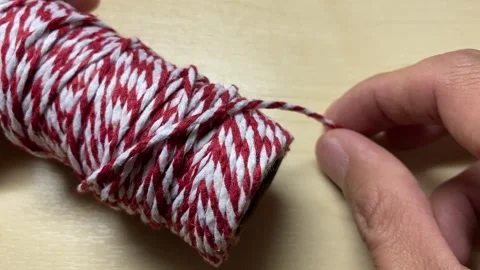 Pulling red and white twine thread close up shot on wooden table. Video stock 248205551