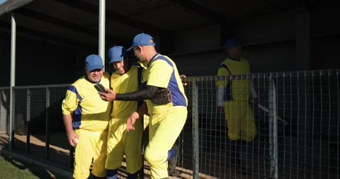 Pulling up smartphone, diverse male baseball teammates clustering by fence on Stock Footage 336366743