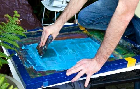 Pulling squeegee across silk screen Stock-Fotos