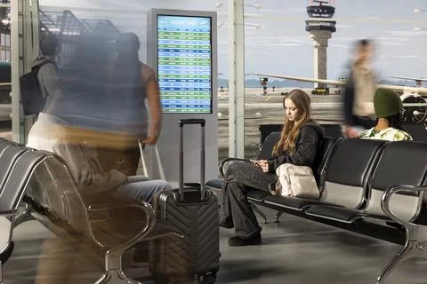 Pulling trolleys, blurry movement and multiethnic tourists in chaotic airport Stock Photos
