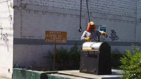 Pulling an underground garbage container with chains from a hydraulic truck Stock Footage 149911192