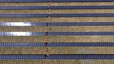Pulling up view on solar array row panels in barren grass field Stock Footage 293429213