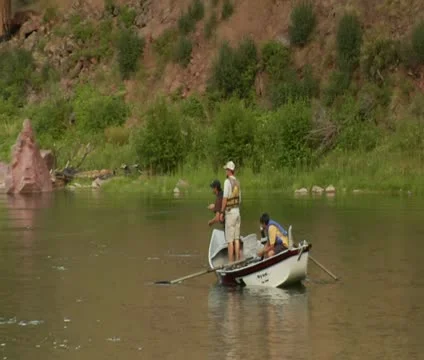 Pullout shot of flyfishing drift boat on calm River with pine tree Stock Footage 21652573