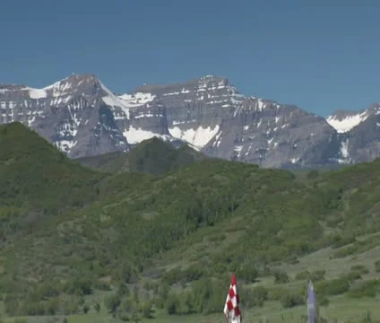 Pullout shot as  Man chips out of sand trap  to green with snowy mountains in Stock Footage 21657667