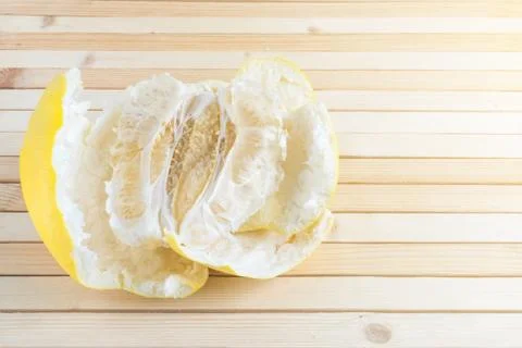 Pulp of ripe exotic fruit pomelo with peel on wooden background in the sun Stock Photos