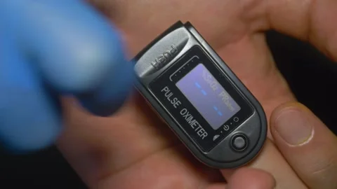 Pulse Oximeter at 98% saturation during patient test in index finger Stock Footage 130854619