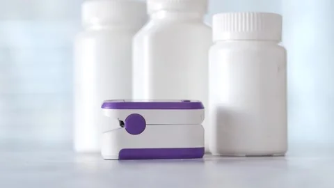 Pulse oximeter and pill bottles on table in shallow depth of field, healthc.. Vídeos de archivo 333033210