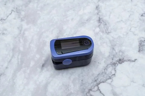 Pulse oximeter digital reading Finger out on marble table top view Stock Photos